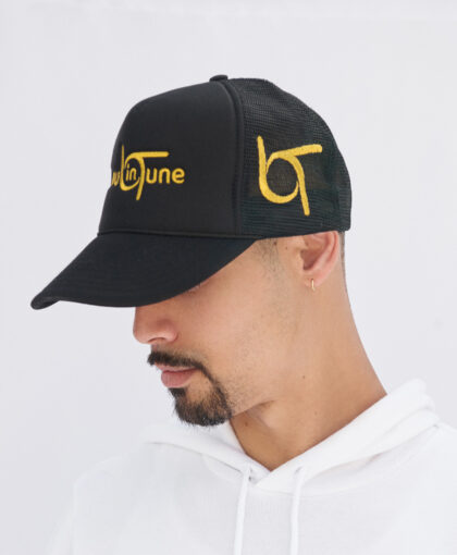 A man wearing a black hat with yellow lettering.