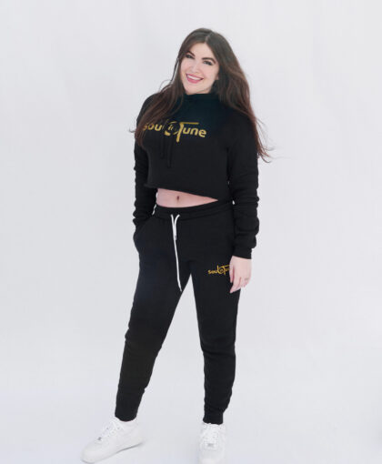 A woman standing in front of the camera wearing black and gold sweatpants.