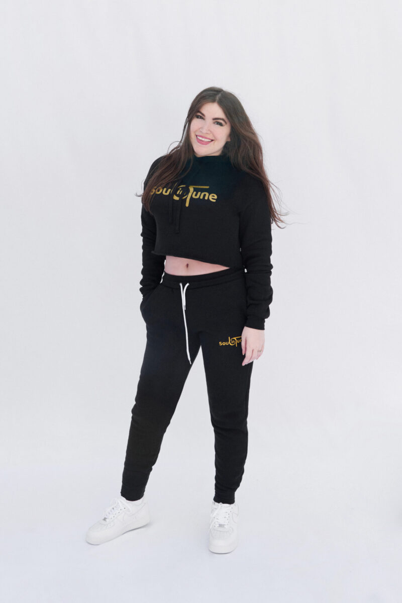 A woman standing in front of the camera wearing black and gold sweatpants.