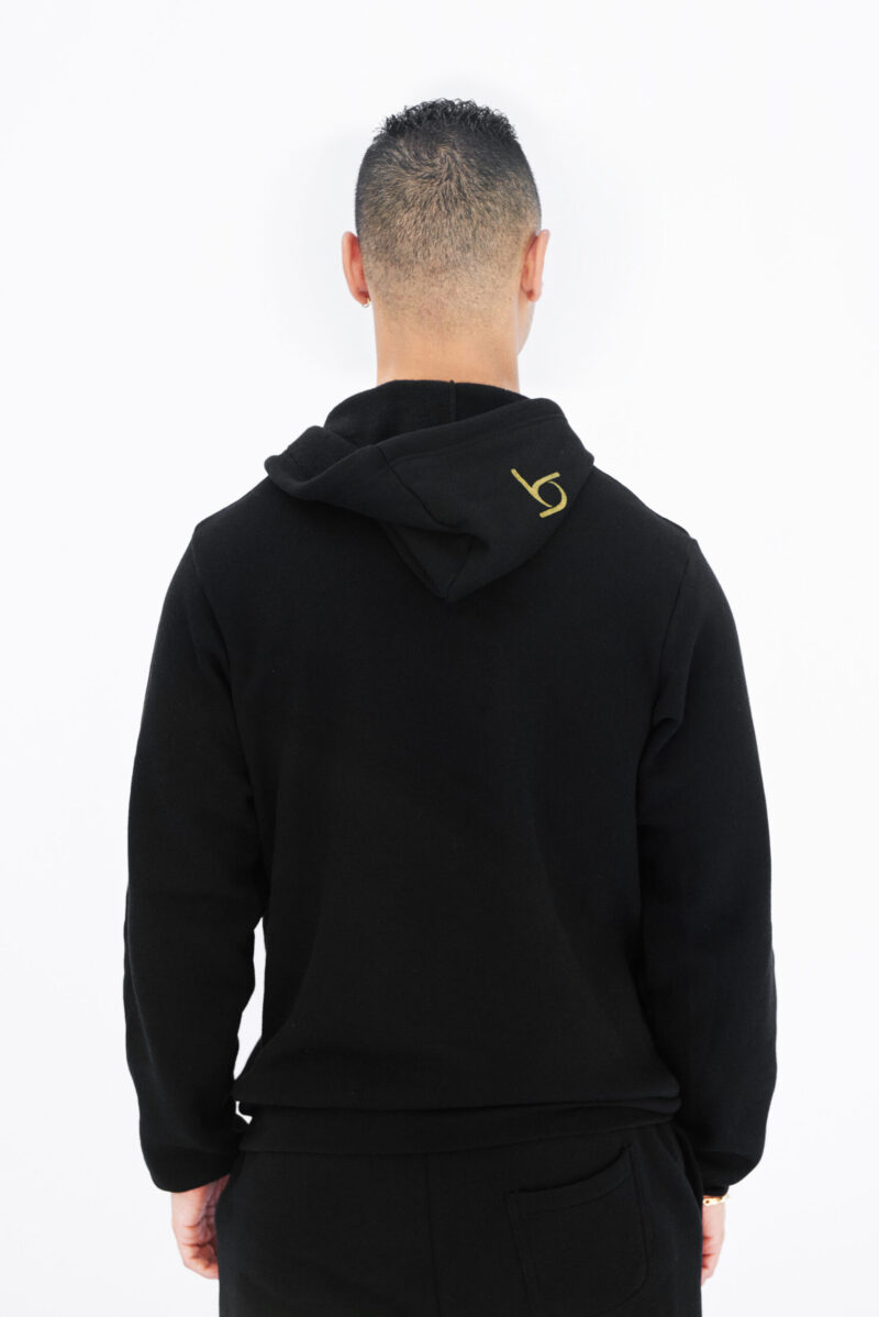 A man wearing a black hoodie with gold lettering.